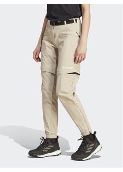 adidas Spodnie dresowe Terrex Utilitas Hiking Zip-Off Tracksuit Bottoms HZ9046 Beżowy Regular Fit ze sklepu MODIVO w kategorii Spodnie męskie - zdjęcie 181045887