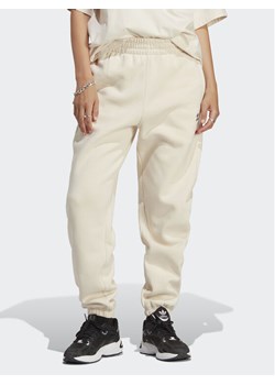 adidas Spodnie dresowe Essentials Fleece IA6436 Écru Regular Fit ze sklepu MODIVO w kategorii Spodnie damskie - zdjęcie 181049536