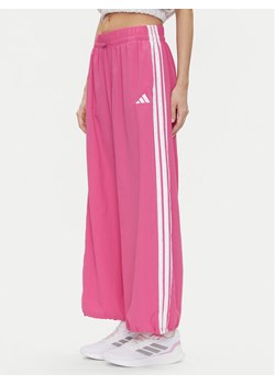 adidas Spodnie dresowe Essentials 3-Stripes JC8167 Różowy Loose Fit ze sklepu MODIVO w kategorii Spodnie damskie - zdjęcie 181088095