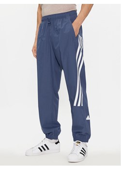 adidas Spodnie dresowe Future Icons 3-Stripes IR9239 Niebieski Slim Fit ze sklepu MODIVO w kategorii Spodnie męskie - zdjęcie 181099945