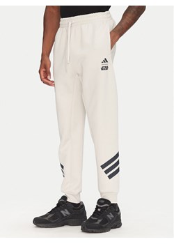 adidas Spodnie dresowe Star Wars The Mandalorian™ JI5723 Beżowy Regular Fit ze sklepu MODIVO w kategorii Spodnie męskie - zdjęcie 181125508