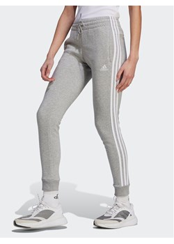 adidas Spodnie dresowe Essentials 3-Stripes IL3282 Szary Slim Fit ze sklepu MODIVO w kategorii Spodnie damskie - zdjęcie 181132617