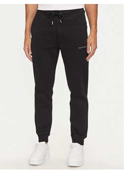 Calvin Klein Jeans Spodnie dresowe Monologo J30J325658 Czarny Regular Fit ze sklepu MODIVO w kategorii Spodnie męskie - zdjęcie 181142138