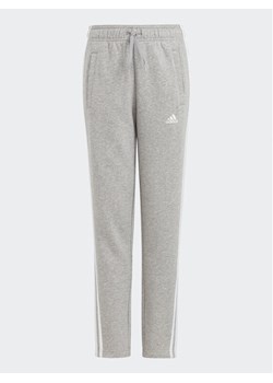 adidas Spodnie dresowe Essentials 3-Stripes IC6127 Szary Slim Fit ze sklepu MODIVO w kategorii Spodnie chłopięce - zdjęcie 181149187