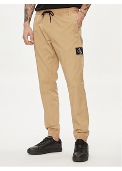 Calvin Klein Jeans Joggery Monologo Badge J30J325114 Beżowy Skinny Fit ze sklepu MODIVO w kategorii Spodnie męskie - zdjęcie 181204287