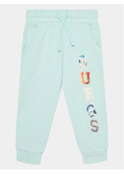 Guess Spodnie dresowe N4GQ11 KA6R3 Niebieski Regular Fit ze sklepu MODIVO w kategorii Spodnie chłopięce - zdjęcie 182606635