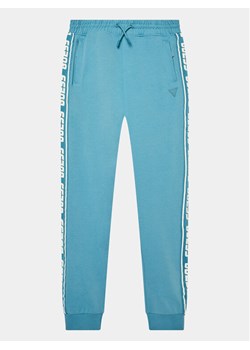 Guess Spodnie dresowe L2YQ48 K6ZS1 Niebieski Regular Fit ze sklepu MODIVO w kategorii Spodnie chłopięce - zdjęcie 182627519