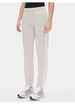 adidas Spodnie dresowe Tricot 3-Stripes JD4536 Beżowy Regular Fit ze sklepu MODIVO w kategorii Spodnie damskie - zdjęcie 182636357