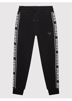 Guess Spodnie dresowe L2YQ48 K6ZS1 Czarny Regular Fit ze sklepu MODIVO w kategorii Spodnie chłopięce - zdjęcie 182638345