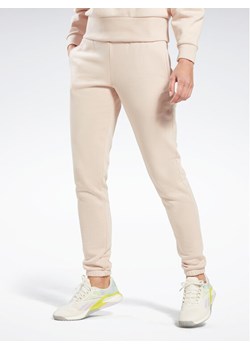 Reebok Spodnie dresowe Fleece IC3502 Beżowy Slim Fit ze sklepu MODIVO w kategorii Spodnie damskie - zdjęcie 182701658