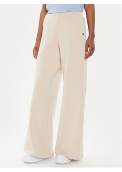 Guess Spodnie dresowe V4YB07 KCAY2 Beżowy Relaxed Fit ze sklepu MODIVO w kategorii Spodnie damskie - zdjęcie 182703649