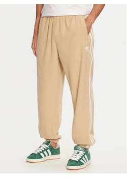 adidas Spodnie dresowe adicolor 3-Stripes IZ2490 Beżowy Regular Fit ze sklepu MODIVO w kategorii Spodnie męskie - zdjęcie 182731285