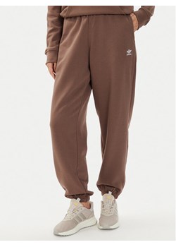 adidas Spodnie dresowe adicolor Essentials IR5974 Brązowy Regular Fit ze sklepu MODIVO w kategorii Spodnie damskie - zdjęcie 183885619