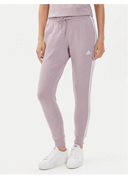 adidas Spodnie dresowe Essentials 3-Stripes IR5379 Różowy Slim Fit ze sklepu MODIVO w kategorii Spodnie damskie - zdjęcie 183945068
