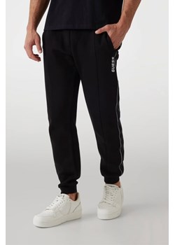 GUESS Czarne męskie spodnie dresowe z lampasami Mickey, Rozmiar S ze sklepu outfit.pl w kategorii Spodnie męskie - zdjęcie 184010866