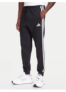 adidas Spodnie dresowe Essential 3-Stripes JD1881 Czarny Regular Fit ze sklepu MODIVO w kategorii Spodnie męskie - zdjęcie 184019446
