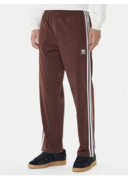 adidas Spodnie dresowe adicolor Classics Firebird KA0482 Brązowy Regular Fit ze sklepu MODIVO w kategorii Spodnie męskie - zdjęcie 185869629