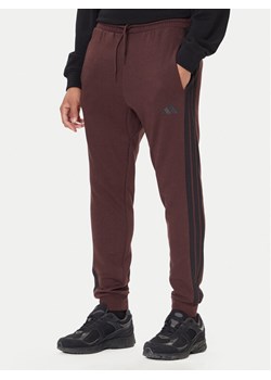 adidas Spodnie dresowe Essentials 3-Stripes JX0749 Brązowy Regular Fit ze sklepu MODIVO w kategorii Spodnie męskie - zdjęcie 186086868