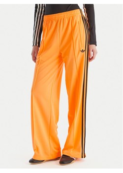 adidas Spodnie dresowe adicolor Classic Firebird JY2694 Żółty Loose Fit ze sklepu MODIVO w kategorii Spodnie damskie - zdjęcie 186521629
