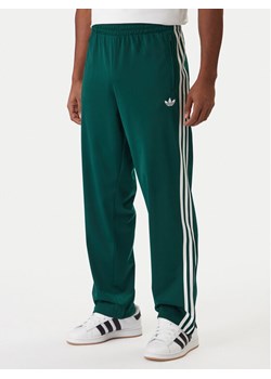 adidas Spodnie dresowe Firebird KD8317 Zielony Loose Fit ze sklepu MODIVO w kategorii Spodnie męskie - zdjęcie 187830997
