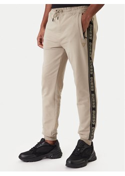 Guess Spodnie dresowe Z2YB19 K6ZS1 Beżowy Regular Fit ze sklepu MODIVO w kategorii Spodnie męskie - zdjęcie 187976037
