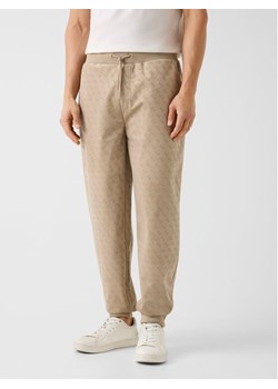 Guess Spodnie materiałowe 180800 Beżowy Regular Fit ze sklepu MODIVO w kategorii Spodnie męskie - zdjęcie 188013247