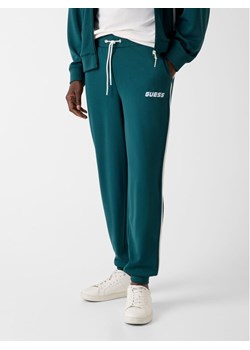 Guess Spodnie dresowe Z6RB13 KD482 Zielony Regular Fit ze sklepu MODIVO w kategorii Spodnie męskie - zdjęcie 188054416