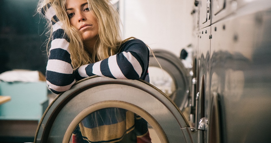 Blondynka w koszulce w paski oparta o drzwi od pralki