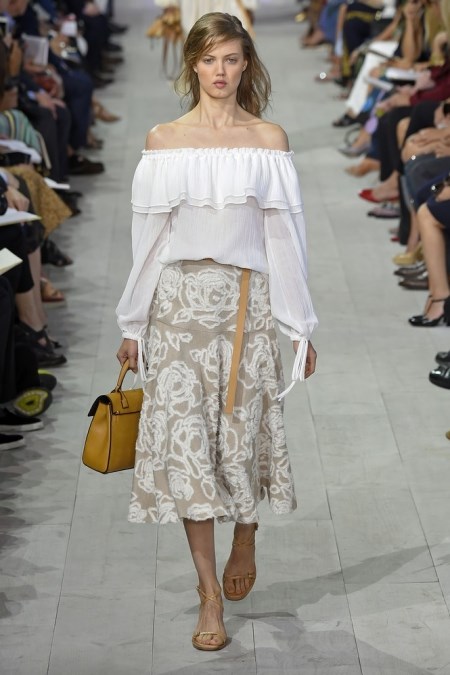 Modelka na wiosenno-letnim pokazie kolekcji Michael Kors w białej bluzce z falbanami.