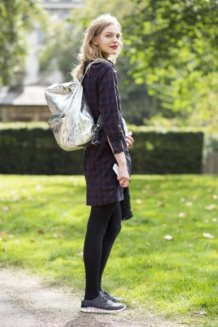 Młoda dziewczyna z metalicznym, srebrnym plecakiem na plecach.