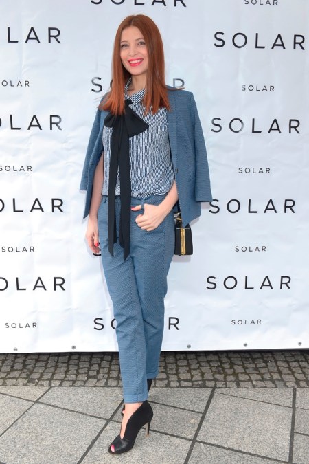 Ada Fijał w grafitowym garniturze damskim i koszuli z czarną wstążką.